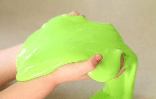 Hands stretching a bright green homemade modeling mixture