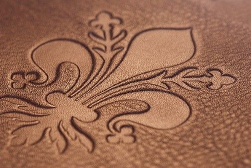 Close-up of a fleur-de-lis design embossed into brown leather