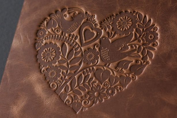 Heart-shaped bird-and-flower design embossed into a piece of brown leather