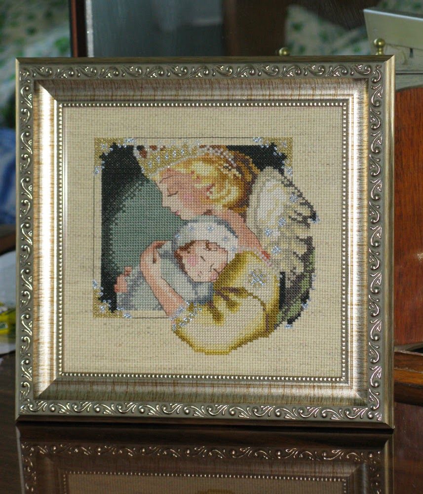 Framed cross-stitch of an angel holding a sleeping baby