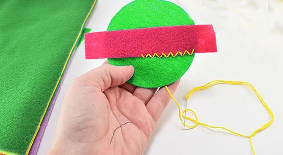 Sewing a red strip onto a green felt piece