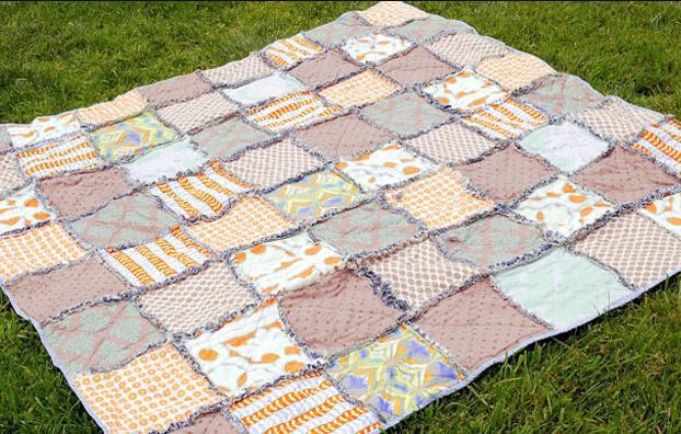Patchwork quilt of light squares laid out on grass