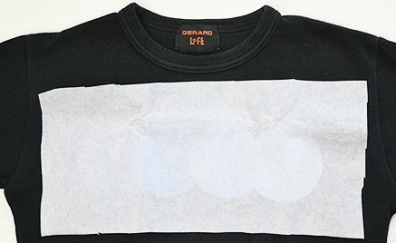 Water-soluble paper over an appliqué on knit fabric