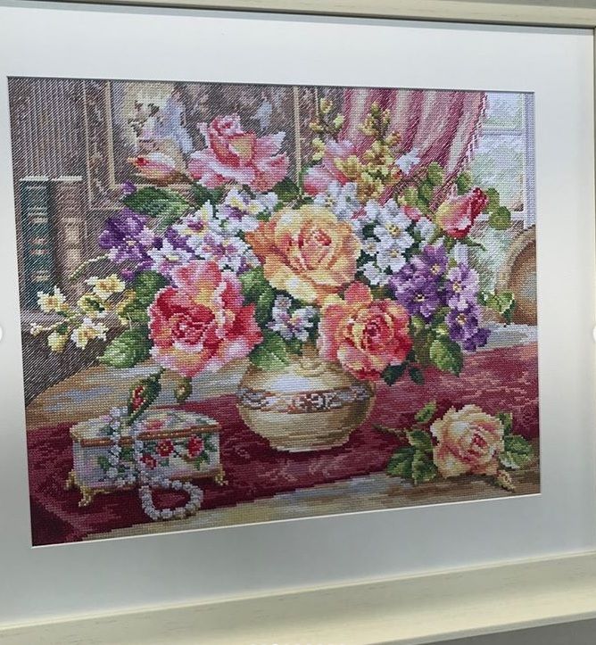 Framed embroidery of a vase of roses and mixed flowers on a table