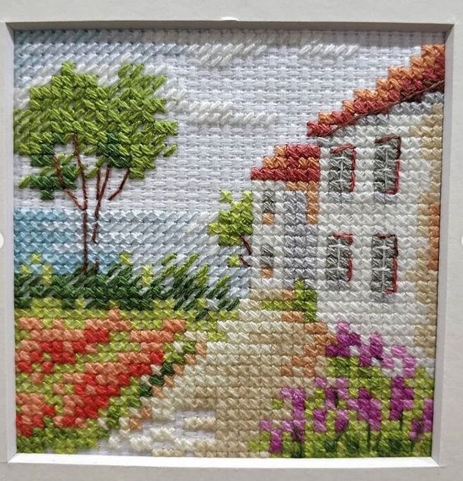 Miniature embroidery of a country house beside a flower-lined path