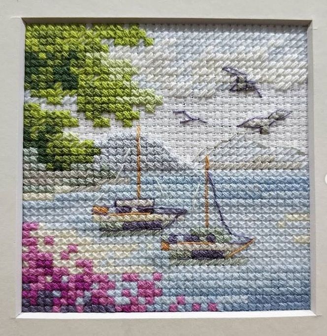 Miniature embroidery of two sailboats near a lighthouse and flying seagulls