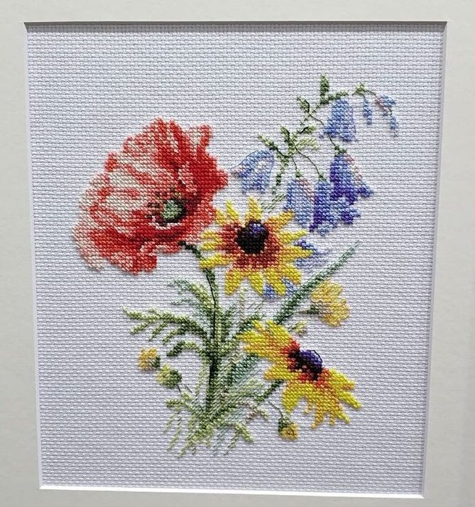Miniature embroidery of poppies, daisies, and blue wildflowers