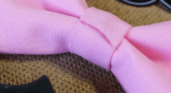 Fabric center band wrapping around the middle of a pink bow tie