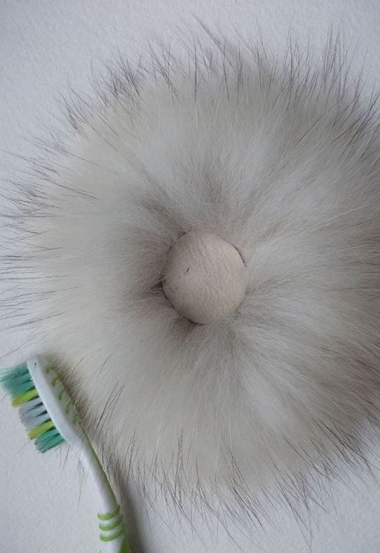 Attaching the brooch's fur base onto white leather