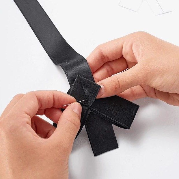 Securing a pleat on the black satin ribbon