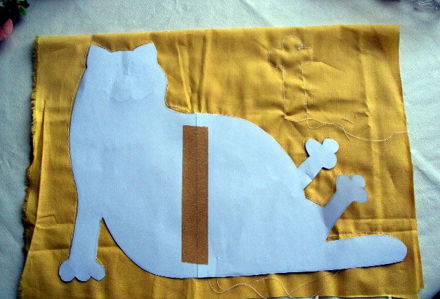 Paper cat pattern traced onto folded yellow fabric