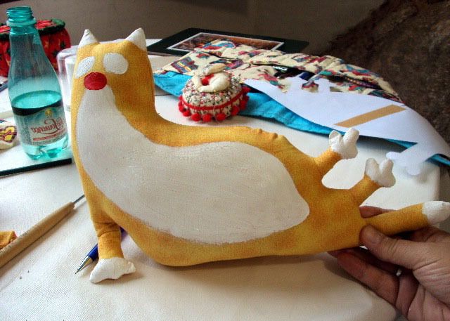 Cat doorstop with white paint on its face, chest, and paws