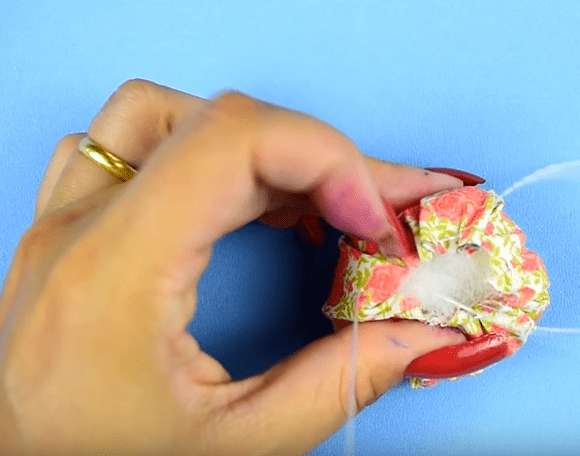 Gathering the fabric around the pincushion stuffing