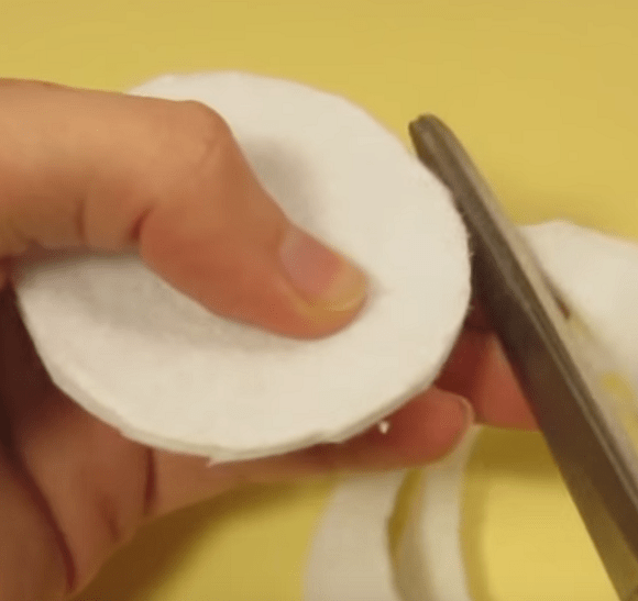 Cutting out a round eye piece from white felt