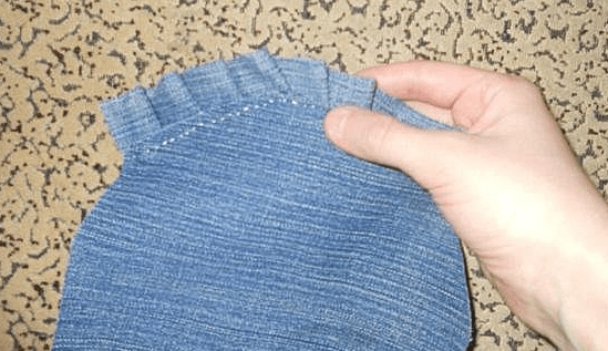 Hand-sewing a gathered ruffle to the lower apron piece with a running stitch