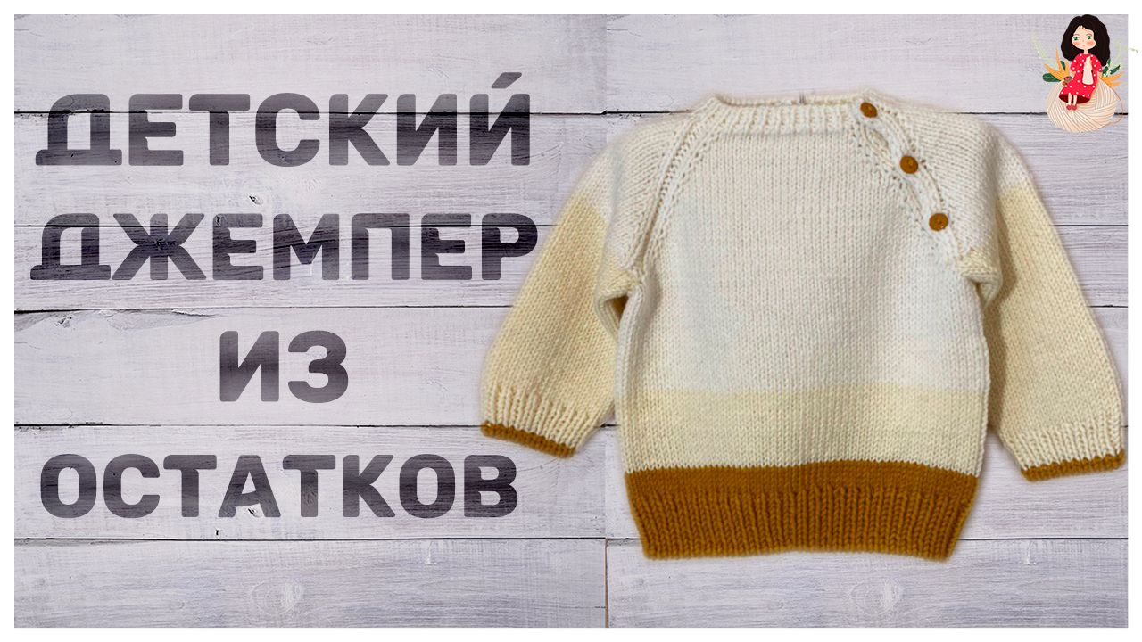 Детский вязаный джемпер молочного цвета с горчичной резинкой и тремя пуговицами у плеча, разложенный на светлых деревянных досках.
