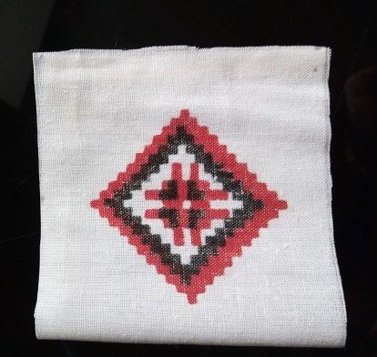 Pincushion with an embroidered diamond on white fabric