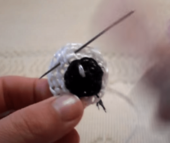 Sewing an eye onto the washcloth's face