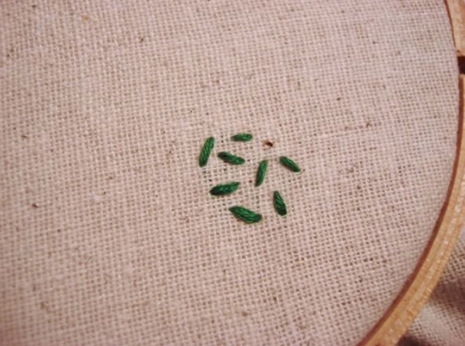 Small circle of green stitches in a hoop
