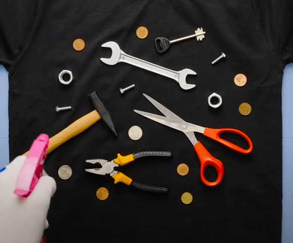 Spraying bleach onto a t-shirt with tools