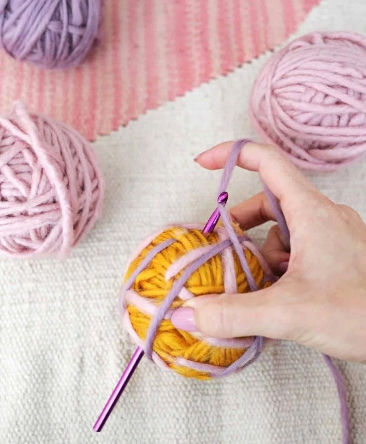 Purple yarn threaded through a yellow yarn ball to secure it