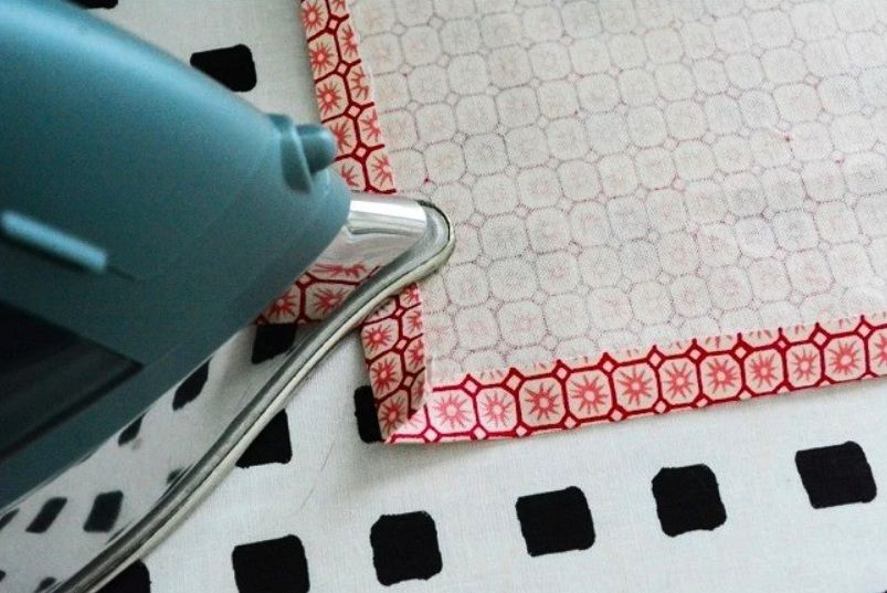 An iron pressing a hem fold at a fabric corner