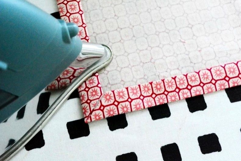 Pressing the hem along the edges of a fabric corner
