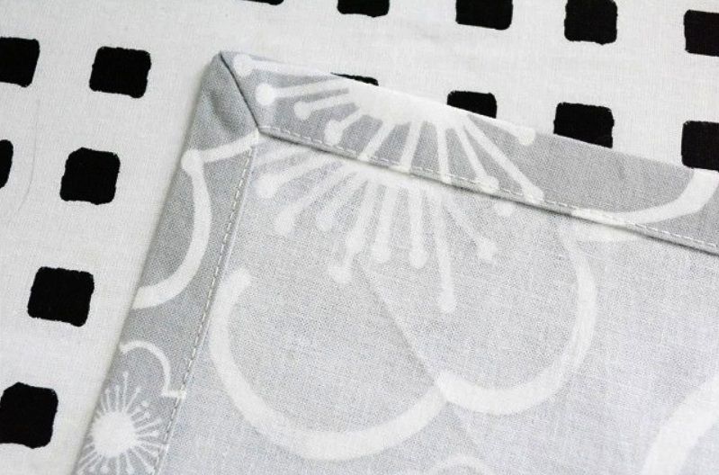 A neatly finished hemmed corner on patterned light-colored fabric