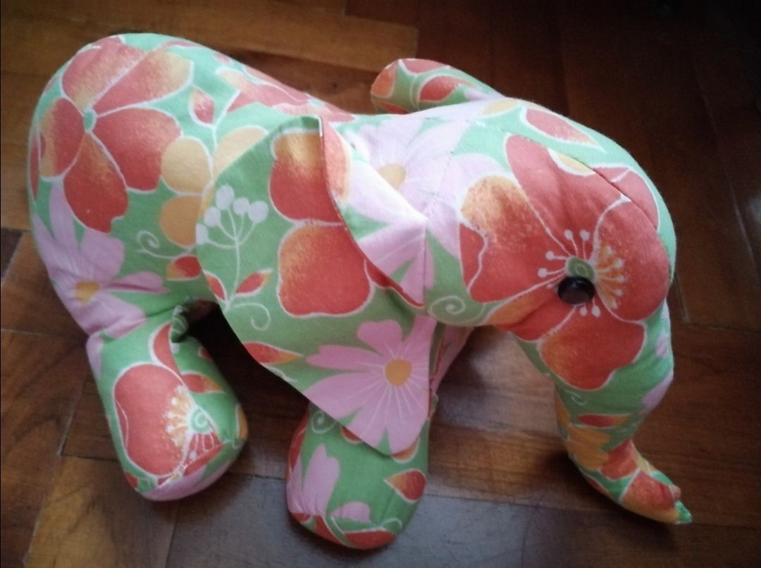Textile elephant made of bright floral fabric, side view