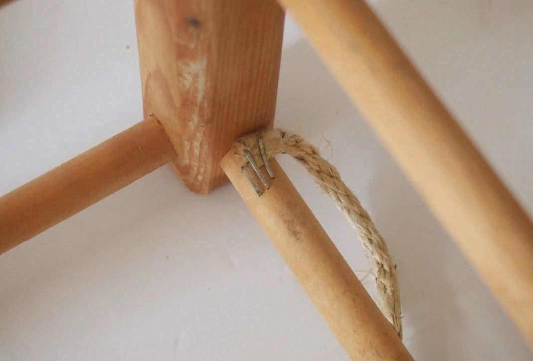 Rope end stapled to the underside of a wooden stool