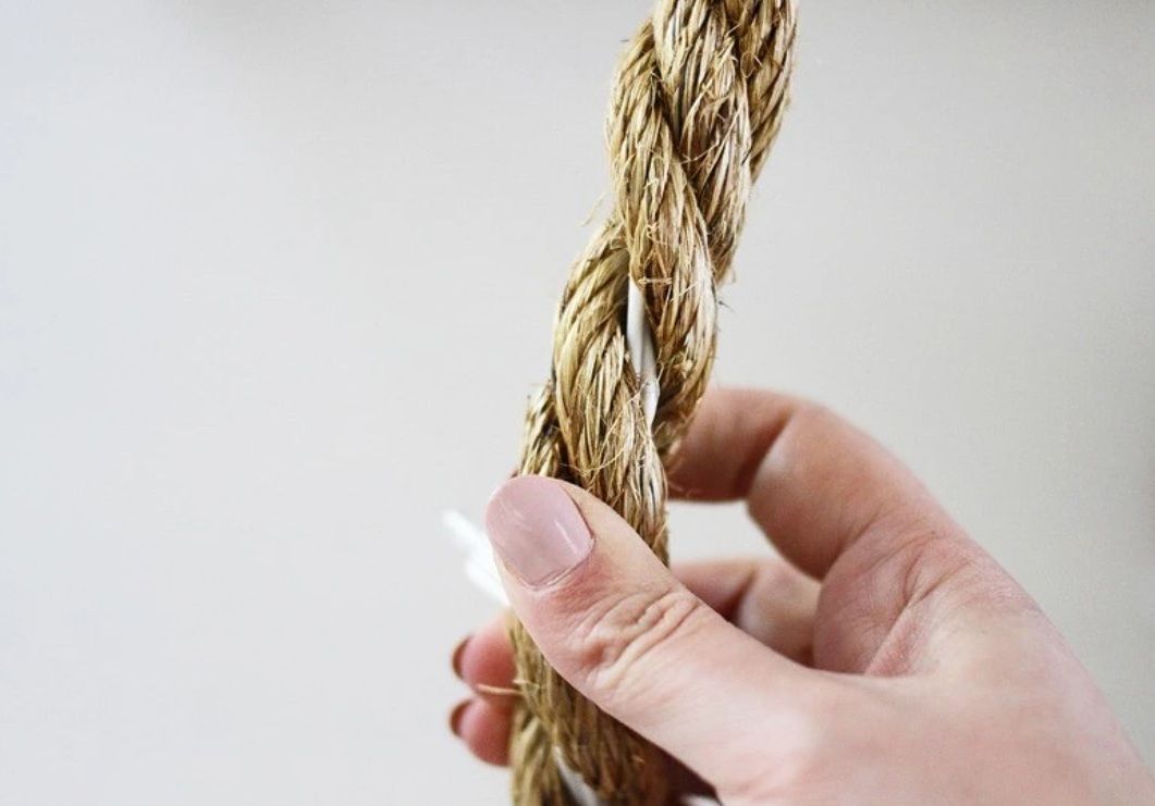 Hand holding rope wrapped around a string of lights