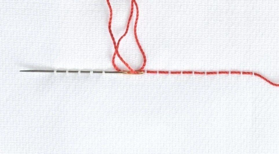 Making the first Swedish embroidery stitch with red thread