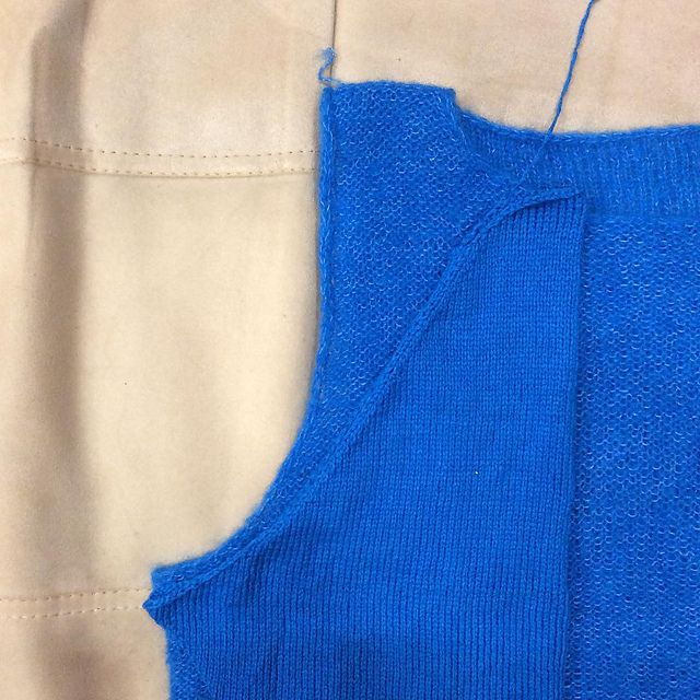 Blue knitted armhole edge shown against a beige fabric piece