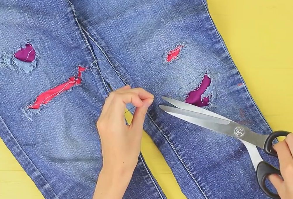 Scissors making additional cuts on kids' jeans