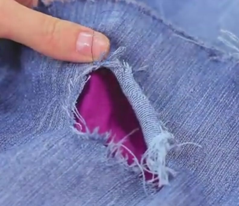 A small tear in jeans with colored fabric underneath