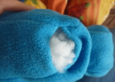 Stuffing a blue puzzle mat piece with polyester batting