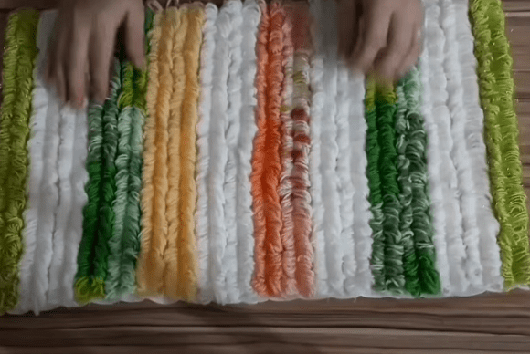 Fabric base covered with stitched yarn loops