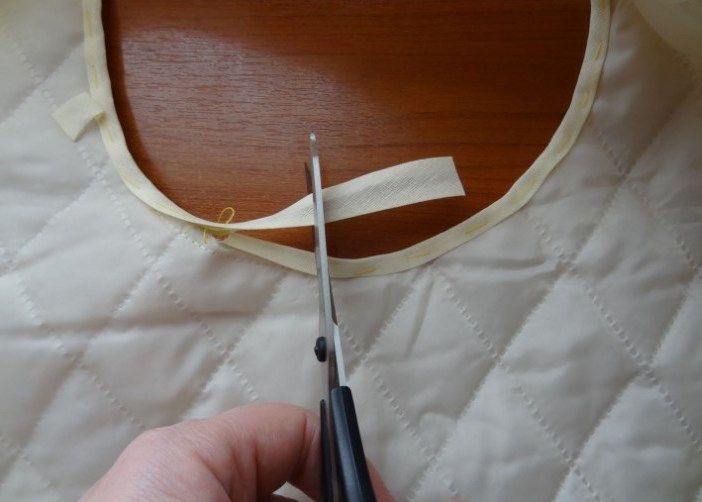 Trimming the excess end of the bias tape at the armhole with scissors