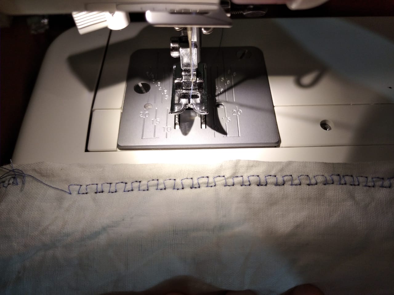 Overlock stitch under the sewing machine presser foot on fabric