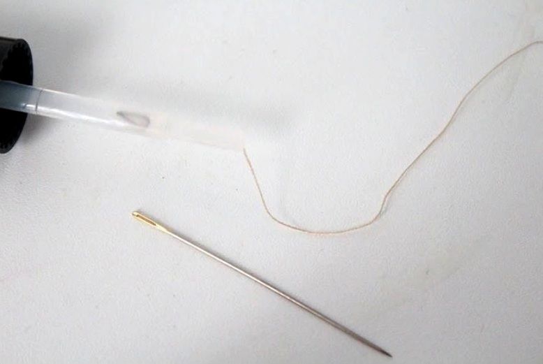 Thread tip coated with nail polish to help it pass through a needle eye