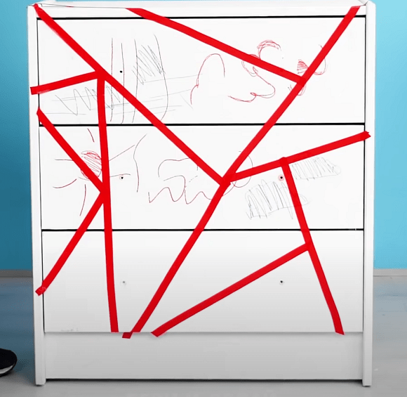 White dresser marked with red painter's tape before painting