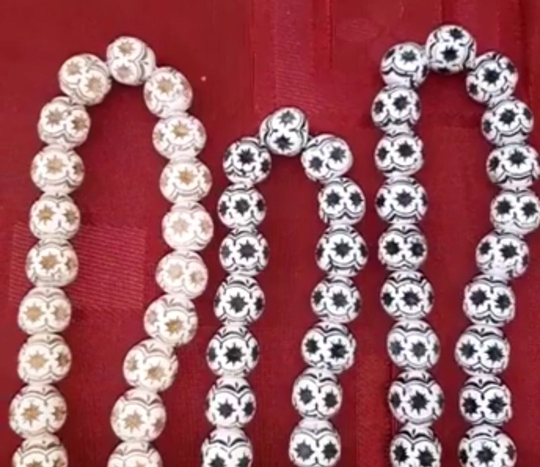 Three strings of round beads on red fabric
