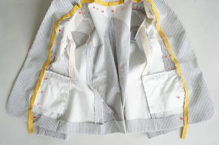 Contrasting piping pinned along the edge of a jacket lining