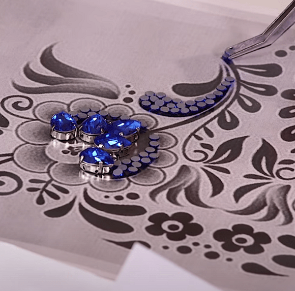 Rhinestones placed on transfer film with tweezers