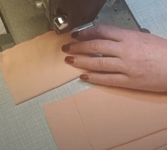 Sewing folded peach knit pieces on a sewing machine