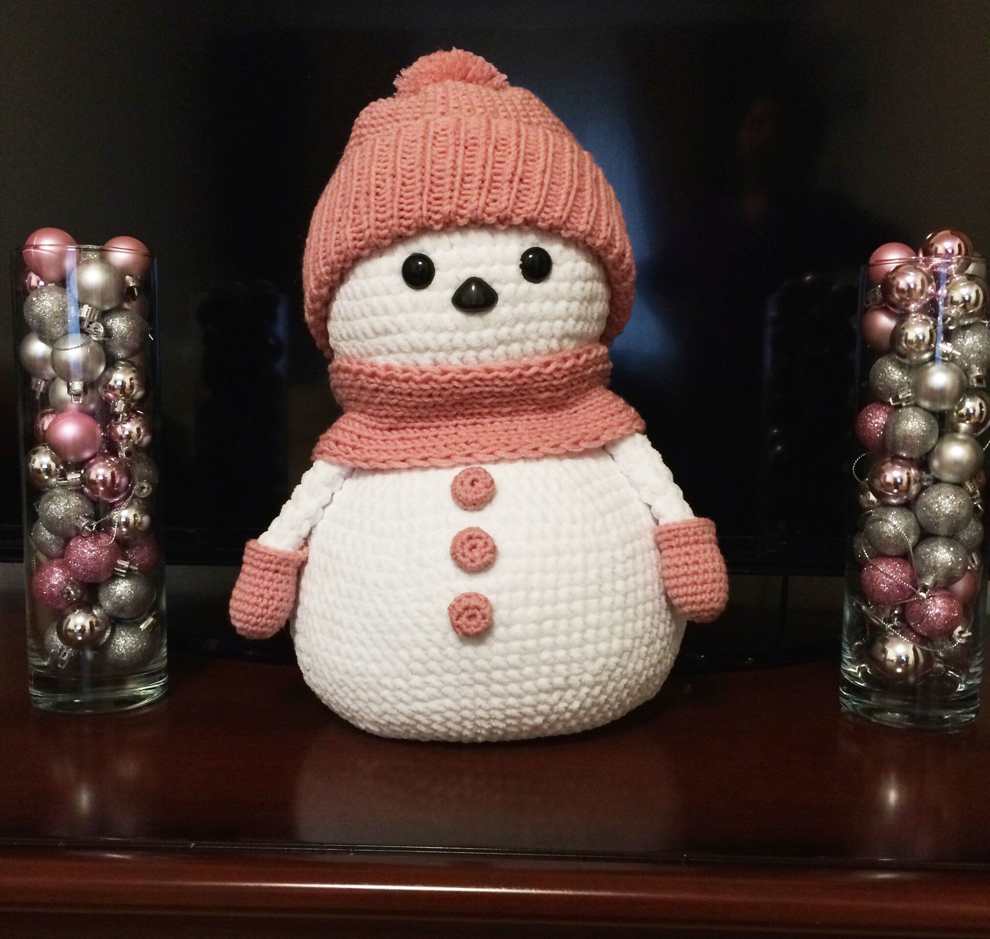 Knitted snowman in a pink hat and scarf