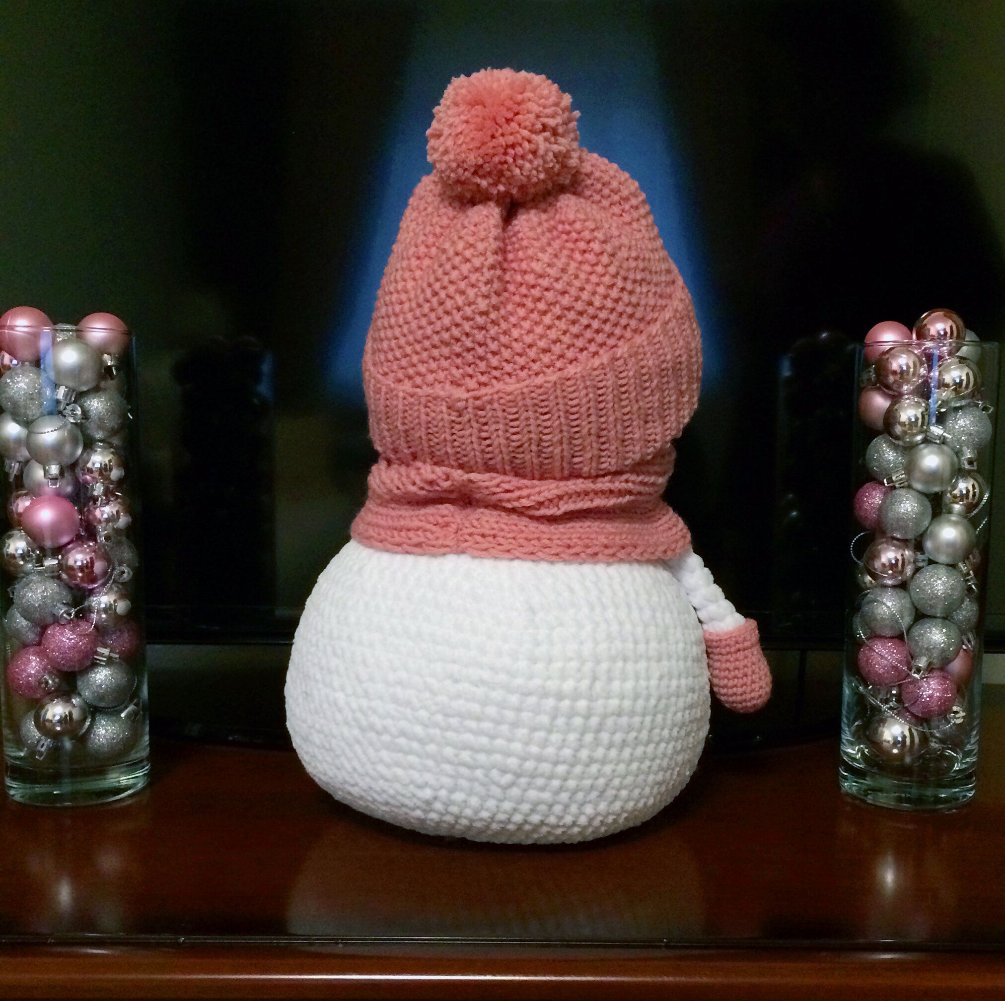 Knitted snowman in a pink hat, back view
