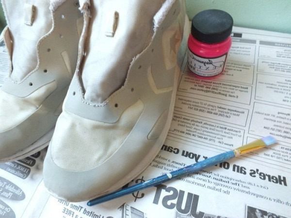 Trainers beside pink fabric paint and a thin brush
