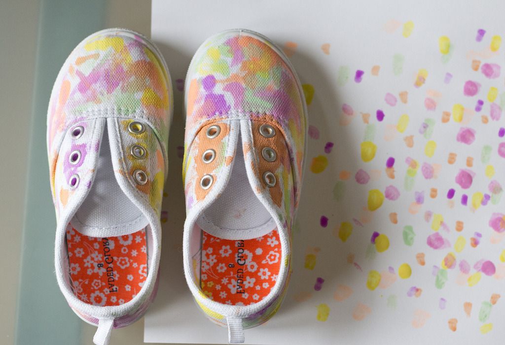 Pastel-painted canvas shoes beside a sheet of painted dots
