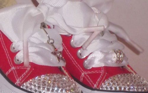 Red children's shoes with bow laces and rhinestone-decorated toe caps